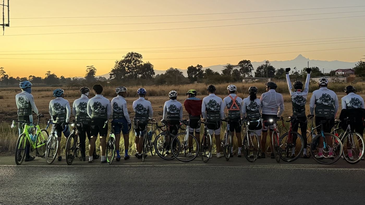 A team of cyclists lined up at sunset, Mount Kenya on the horizon